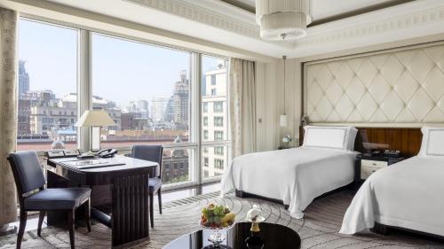 a hotel room with a bed and a desk and a large window at The Peninsula Shanghai in Shanghai
