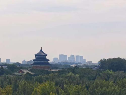 a pagoda in the distance with a city in the background at Beijing Manxin Temple of Heaven North Gate Hotel in Beijing