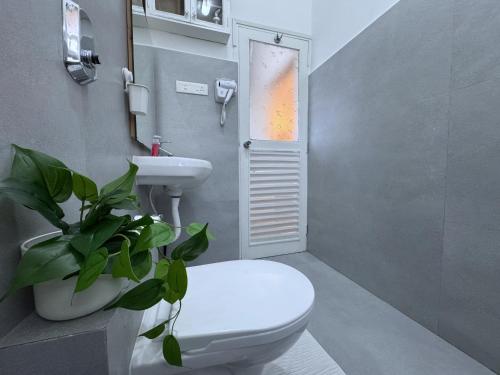 a bathroom with a toilet and a sink and a plant at Nestwood - By The Beach Goa in Benaulim