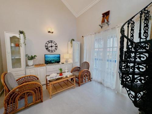 a living room with a table and chairs and a clock at Nestwood - By The Beach Goa in Benaulim