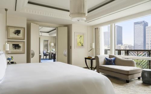 a bedroom with a bed and a chair and a balcony at The Peninsula Shanghai in Shanghai