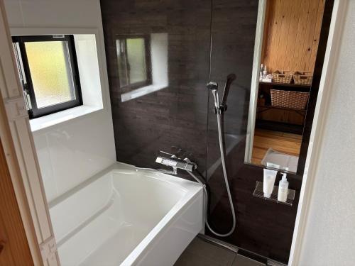 a bathroom with a white tub and a shower at ゲストハウス八咫 in Tanabe