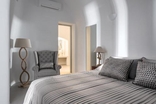 a white bedroom with a bed and a chair at Sensation Villa - by Senses Collection in Pyrgos