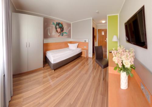 a bedroom with a bed and a vase of flowers at attimo Hotel Stuttgart***S in Stuttgart