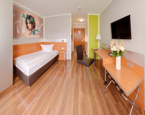 a hotel room with a bed and a desk and a tv at attimo Hotel Stuttgart***S in Stuttgart