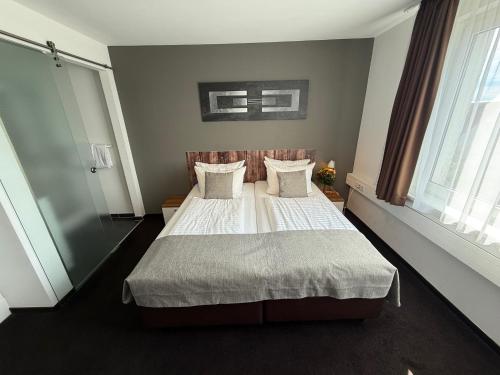 a bedroom with a bed with white sheets and pillows at Hotel Aviva in Leipzig