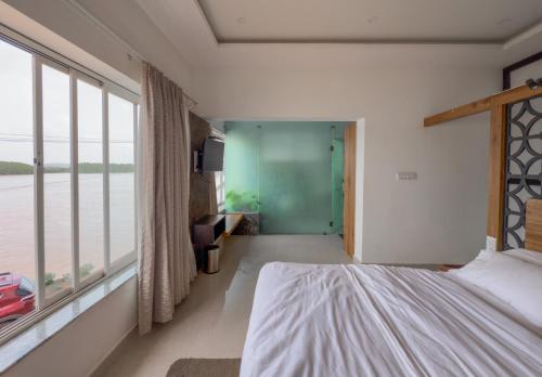 a bedroom with a bed and a large window at Nadhi Mane River-front Beach Stay in Tadri