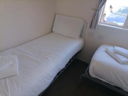 a small room with two beds and a window at Acer Leaf - 2 bedrooms sleeps 6 in Camber