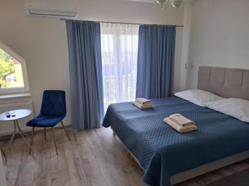 a bedroom with a bed and a blue chair and a window at Restauracja -Zajazd trzech braci in Cieszyn