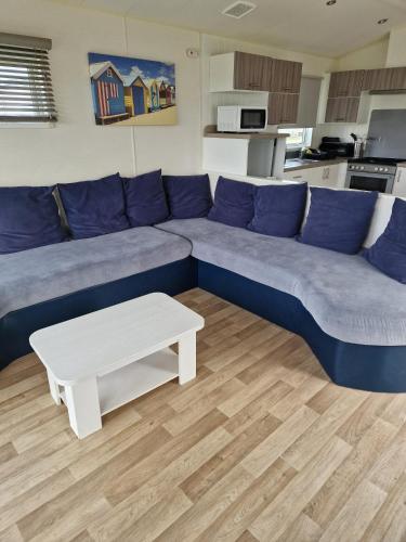 a living room with a blue couch and a white coffee table at Acer Leaf - 2 bedrooms sleeps 6 in Camber
