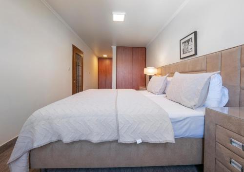 a bedroom with a large bed with white sheets and pillows at Ambassador Apartments in Petrovac na Moru