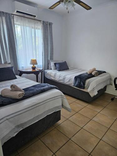 a bedroom with two beds and a window at Hillton Manor Guest House in Richards Bay