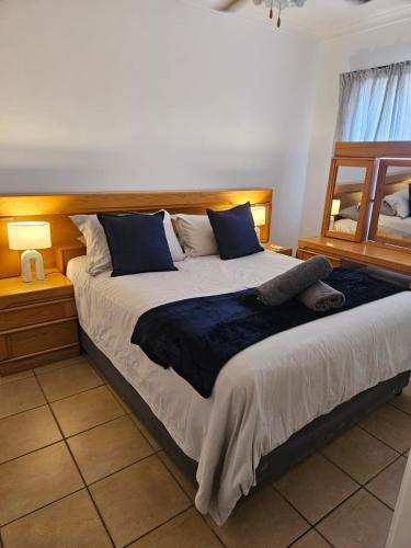 a bedroom with a large bed with blue pillows at Hillton Manor Guest House in Richards Bay