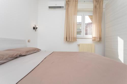 a white bedroom with a bed and a window at Sentiti A Casa - Bronte in Bronte