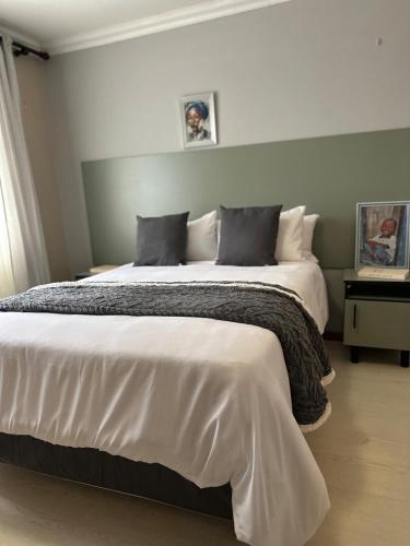 a bedroom with a large bed with white sheets and pillows at Bisho Grand Escape in Bisho