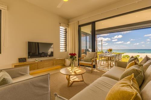 a living room with a couch and a tv and the ocean at Le Dalblair by Horizon Holidays in Pointe d'Esny