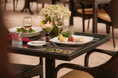 a table with two plates of food and glasses of wine at Sheraton Ankara Hotel & Convention Center in Ankara