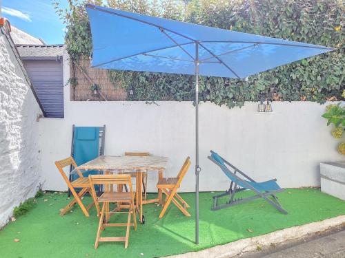 a table and chairs with a blue umbrella at La Flibuste, Vue Mer, Plage à Pied & Parking in Plérin
