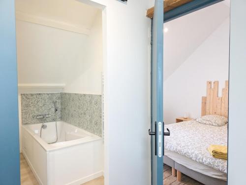 a bathroom with a bath tub next to a bed at La Flibuste, Vue Mer, Plage à Pied & Parking in Plérin