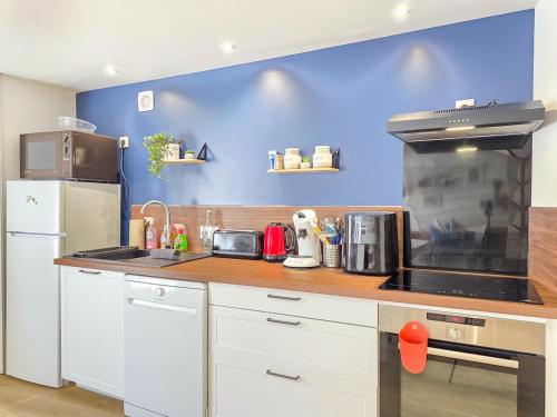 a kitchen with white cabinets and a blue wall at La Flibuste, Vue Mer, Plage à Pied & Parking in Plérin