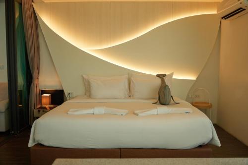 a bedroom with a white bed with two pillows at Whale Hua Hin - SHA Plus in Hua Hin