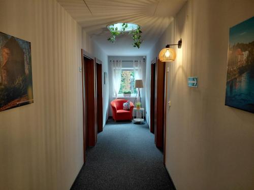 a hallway with a red chair and a window at Gościniec nad Olzą in Cieszyn
