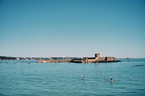 a group of people on paddle boards in the water at Large one bedroom beach apartment in Bel Royal