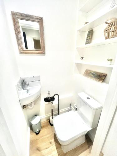 a white bathroom with a toilet and a sink at Large one bedroom beach apartment in Bel Royal