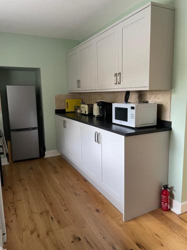 a kitchen with white cabinets and a white microwave at Oldwood. Fyvie. in Turriff