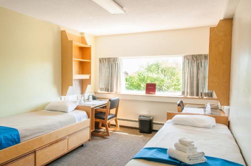 um quarto com 2 camas, uma secretária e uma janela em Saint Mary's University Conference Services & Summer Accommodations em Halifax