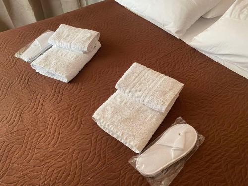 two towels and a pair of shoes on a bed at Despoina Apartments in Edipsos