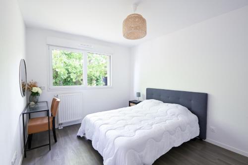a white bedroom with a large bed and a table at Bienvenue - 500 m de la plage in Courseulles-sur-Mer