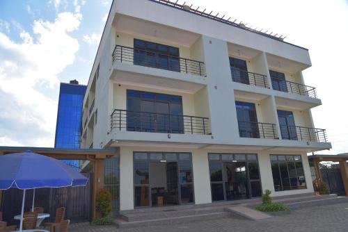 a white building with an umbrella in front of it at Kanamba invent hotel in Kasese