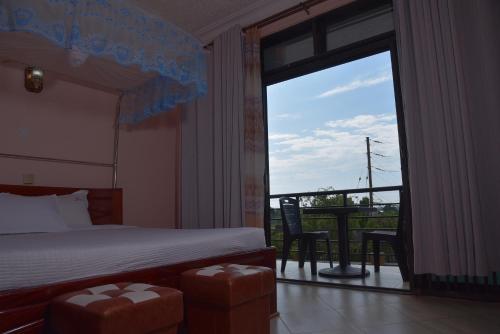 a bedroom with a bed and a view of a balcony at Kanamba invent hotel in Kasese