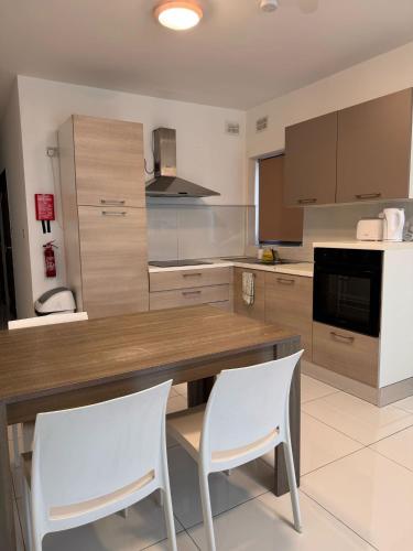 a kitchen with a wooden table and two white chairs at Large Penthouse In Cenrtal Area in Il-Gżira
