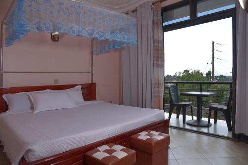 a bedroom with a bed and a balcony with a table at Kanamba invent hotel in Kasese