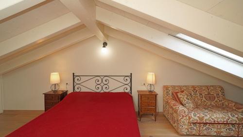 una camera da letto con un letto rosso e un divano di Garda Prestige Retreat a Moniga