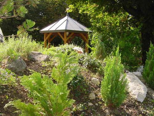 a wooden gazebo in the middle of a garden at Hotel Restaurant Belvedere in Weissbad