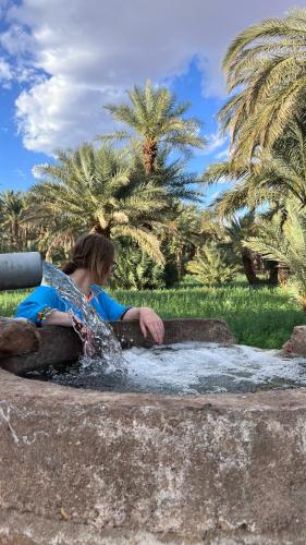 a woman sitting in the water in a fountain at Kasbah Hnini in Igdourane