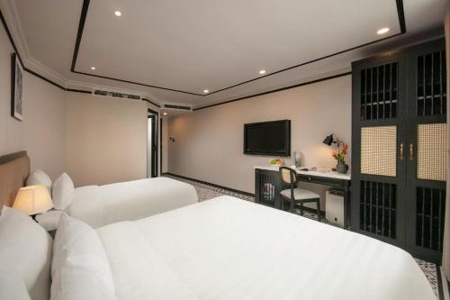 a hotel room with two beds and a desk at Paradise Grand Center Hanoi Hotel in Hanoi