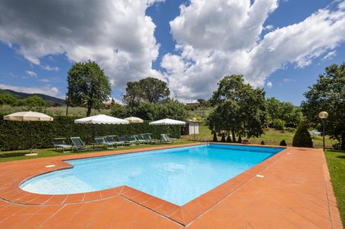 a swimming pool in a yard with chairs and umbrellas at Campo Grande by VacaVilla in Santa Cristina