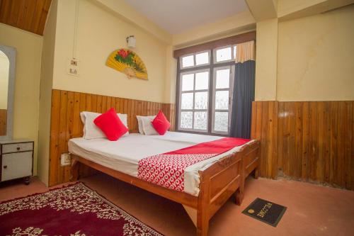 a bedroom with a bed with red pillows and a window at Hotel O Siljong in Gangtok