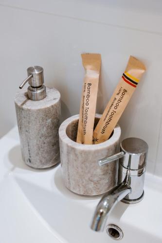 a bathroom sink with two containers with toothbrushes at Slow Moments in Brussels in Brussels