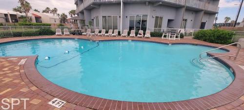 a large blue swimming pool with chairs and a building at Aquarius 408 in South Padre Island