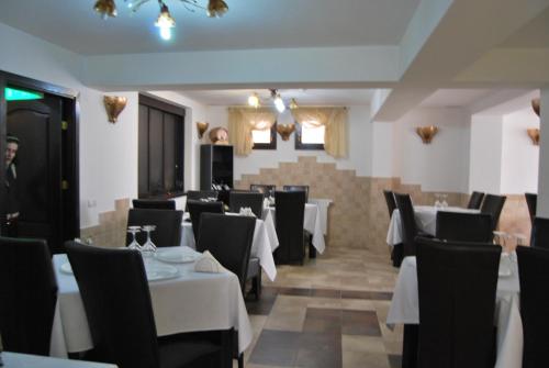 a dining room with white tables and black chairs at Pensiunea Gold in Durau