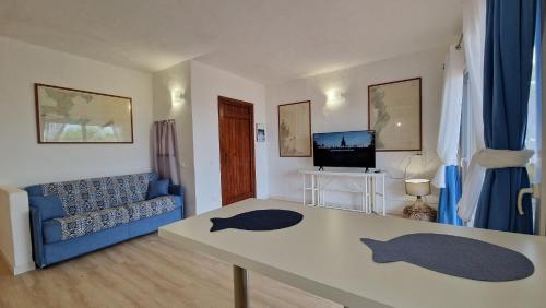 a living room with a table and a blue couch at Villaggio Est a Capo Coda Cavallo San Teodoro in San Teodoro