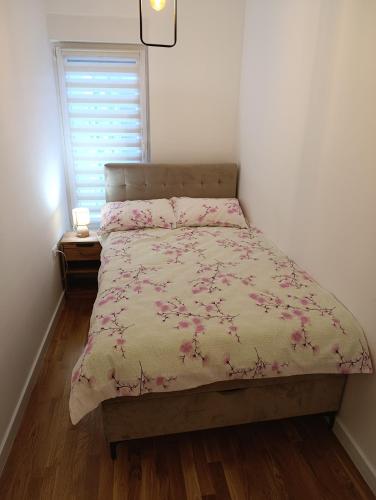 a bedroom with a bed with pink flowers on it at Apartman ANATEO in Vranješ