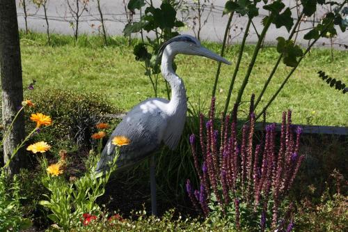 a statue of a bird in a garden with flowers at Haus Reiher am Lauwersmeere176 in Anjum
