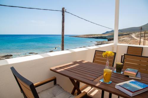 a wooden table on a balcony with a view of the ocean at Waterfront Bliss in Diakofti, Kythira 2 Bedroom in Dhiakofti