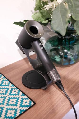 a black hair drier sitting on a table with a vase at The Shantipan Jasmine - Cozy City Retreat 400m from BTS Station in Bangkok